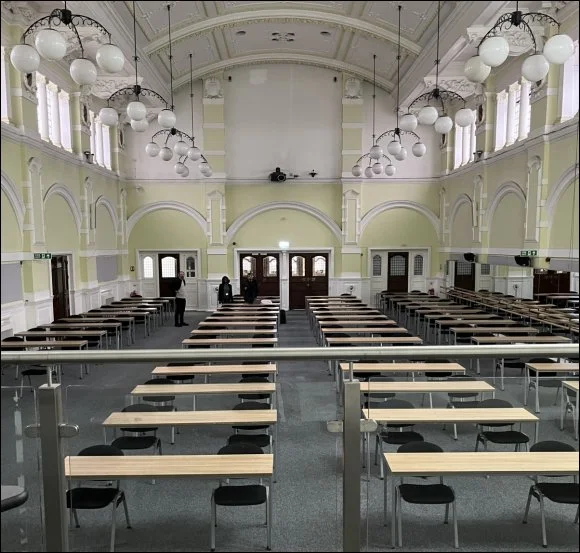 The Great Hall in mid 2023 when it was set up as an exam room with well spaced tables and chairs for 112 people - at the far end three of the BCLH24 team can be seen